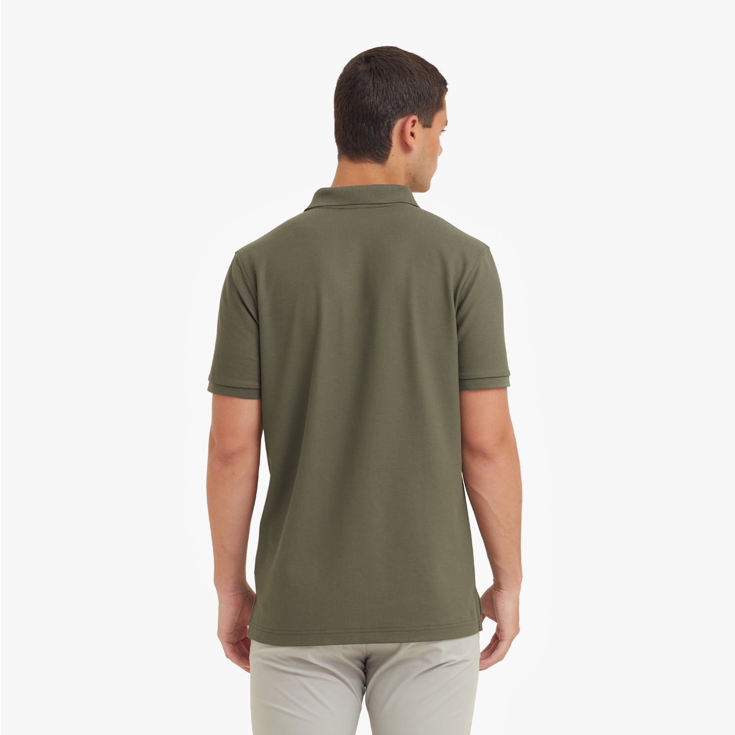 Back view of a man wearing a green polo shirt on a white background