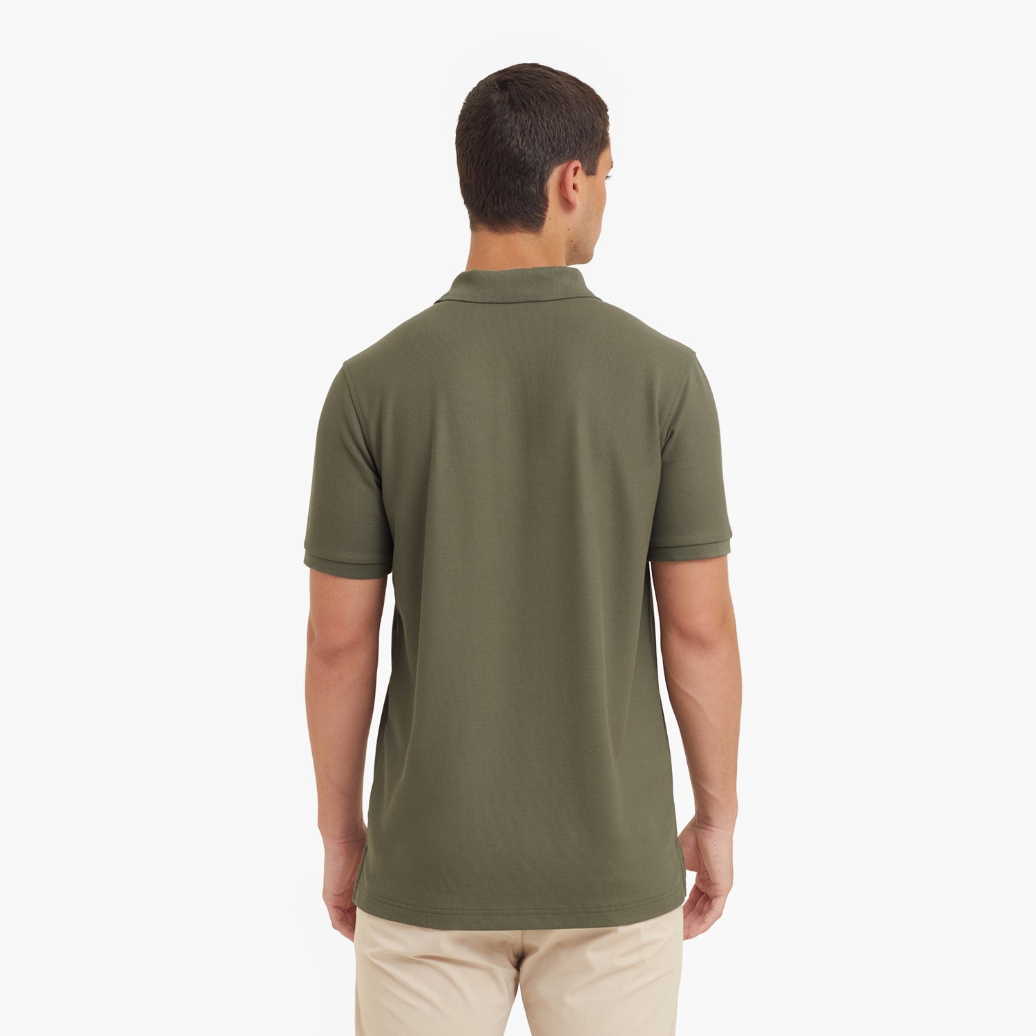 Back view of a man wearing a green polo shirt on a white background