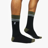 Black socks with green accents worn by a person on a white background