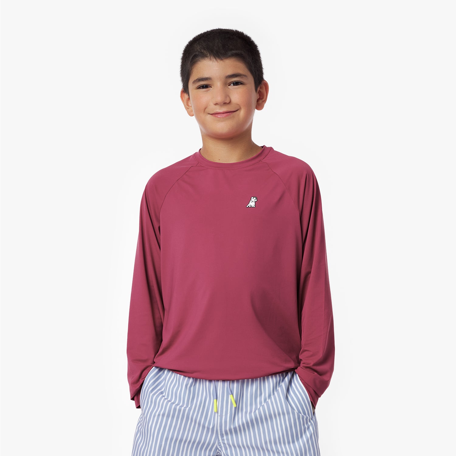 Child wearing a maroon long-sleeve rashguard with a logo