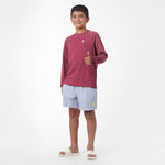 Child wearing a maroon long-sleeve rashguard and striped shorts on a white background