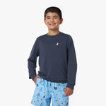 Child wearing a navy long-sleeve rashguard and blue shorts with a pattern