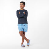 Child wearing a navy rashguard and light blue shorts with a pattern on a white background