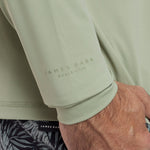Close-up of a light green rashguard with 'James Bark Beach Club' branding