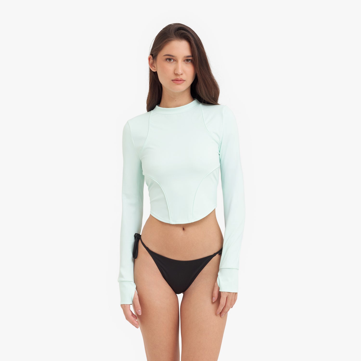 Woman wearing a light green long-sleeve rashguard and black bikini bottoms