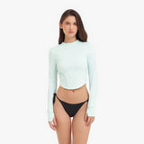 Woman wearing a light green long-sleeve rashguard and black bikini bottoms