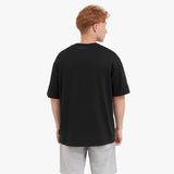 Back view of a man wearing a black t-shirt and gray shorts on a white background