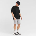 Man wearing a black t-shirt, gray shorts, and black and white sneakers on a white background
