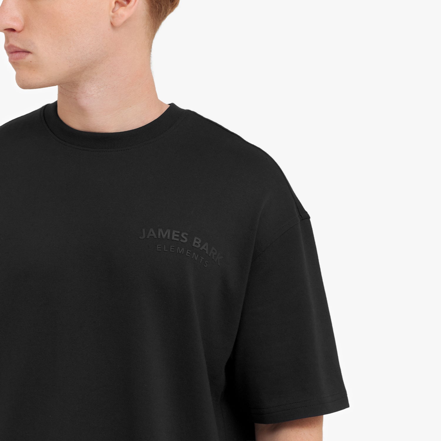 Close-up of a man wearing a black t-shirt with the 'James Bark' logo on a white background