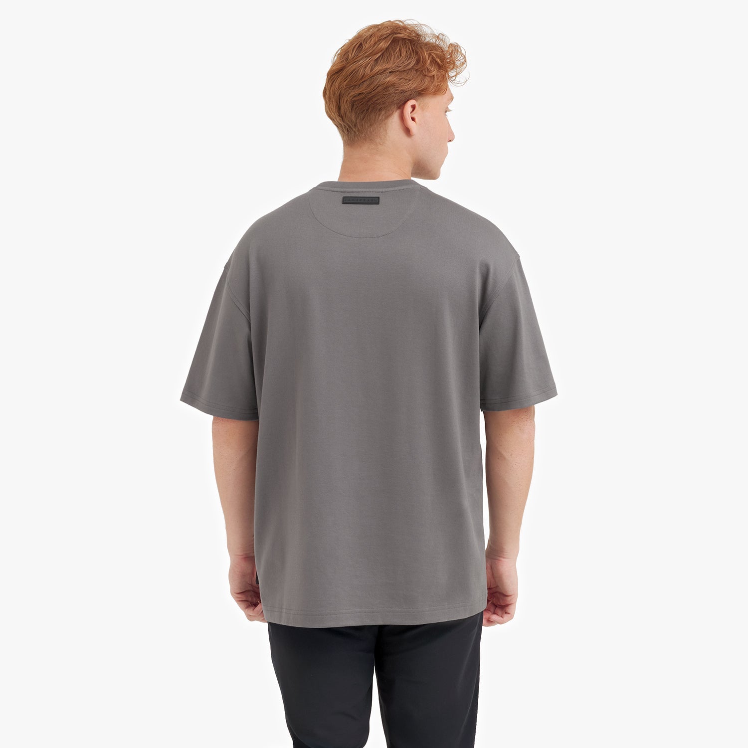 Back view of a man wearing a gray t-shirt on a white background