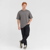 Man wearing a gray t-shirt and black pants on a light gray background