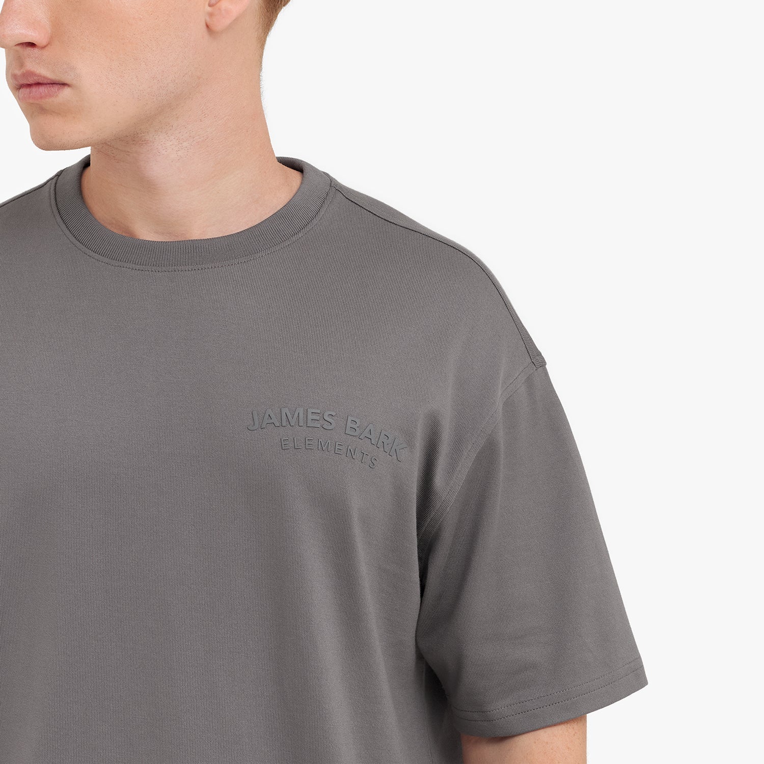 Close-up of a gray t-shirt with 'JAMES BARK' logo on a white background