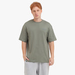 Man wearing a green t-shirt and gray pants on a white background