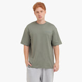 Man wearing a green t-shirt and gray pants on a white background