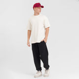 Person wearing a white t-shirt, black pants, and a red cap on a white background