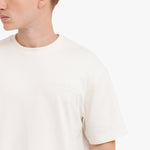 Close-up of a person wearing a plain white t-shirt on a light beige background