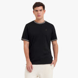 Man wearing a black t-shirt with white trim on a white background