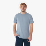 Man wearing a light blue t-shirt and dark pants on a white background