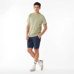Full body picture of a man wearing a light green t-shirt and navy shorts on a white background