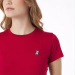 Close-up of a red t-shirt with a small logo worn by a person on a white background