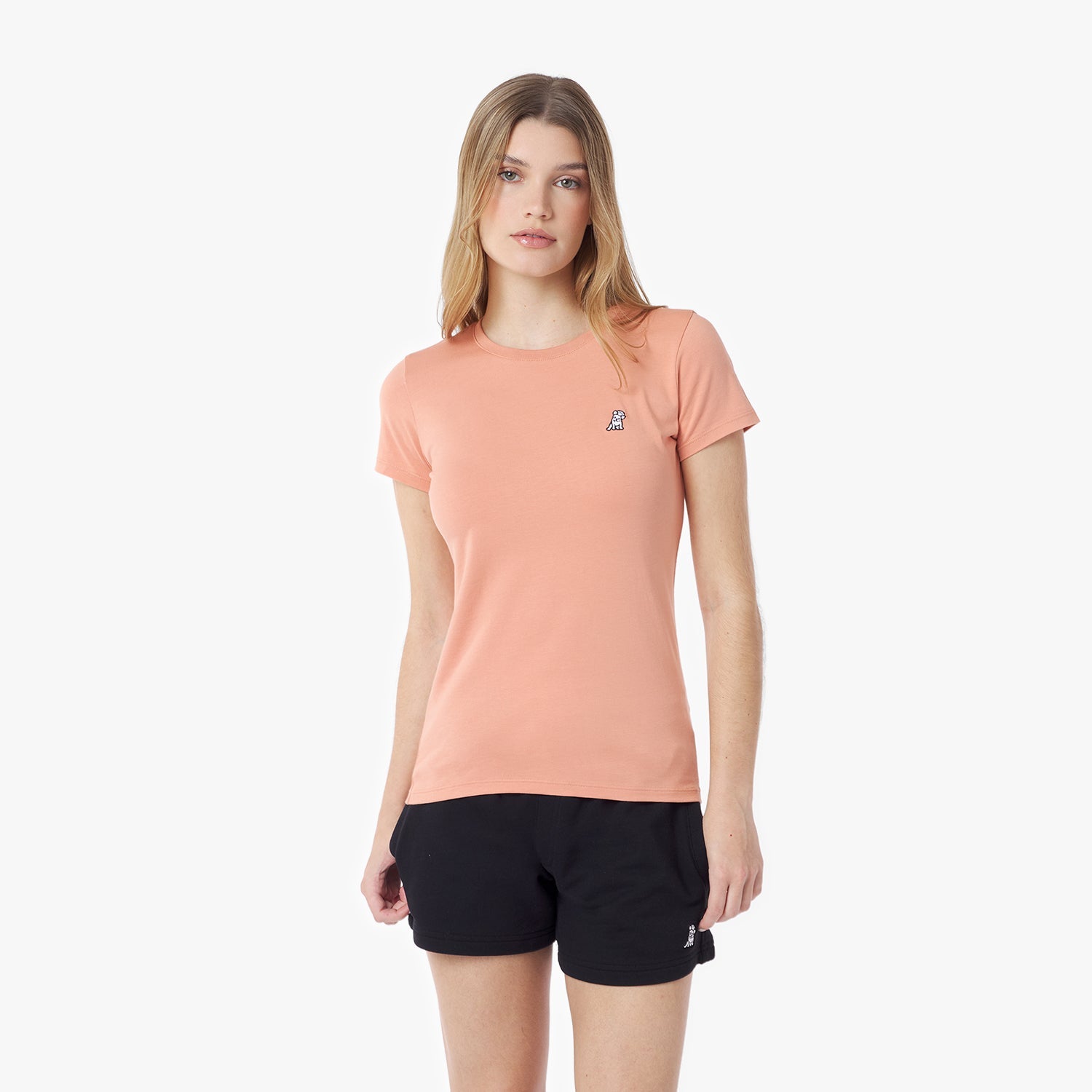 Woman wearing a peach t-shirt and black shorts on a white background