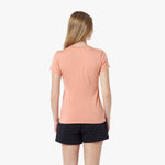 Back view of a woman wearing a peach t-shirt and black shorts on a white background