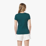 Back view of a woman wearing a teal t-shirt and white shorts on a white background