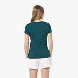Back view of a woman wearing a teal t-shirt and white shorts on a white background