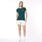 Woman wearing a green t-shirt and white shorts on a white background