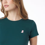 Close-up of a woman wearing a green t-shirt with a small pink logo on a white background