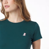 Close-up of a woman wearing a green t-shirt with a small pink logo on a white background