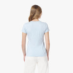 Back view of a woman wearing a light blue t-shirt and white pants on a white background