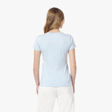 Back view of a woman wearing a light blue t-shirt and white pants on a white background