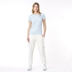 Woman wearing a light blue t-shirt and white pants on a white background