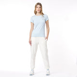 Woman wearing a light blue t-shirt and white pants on a white background