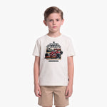 A young boy modeling a cream-colored t-shirt with a James Barker racing graphic, paired with khaki shorts