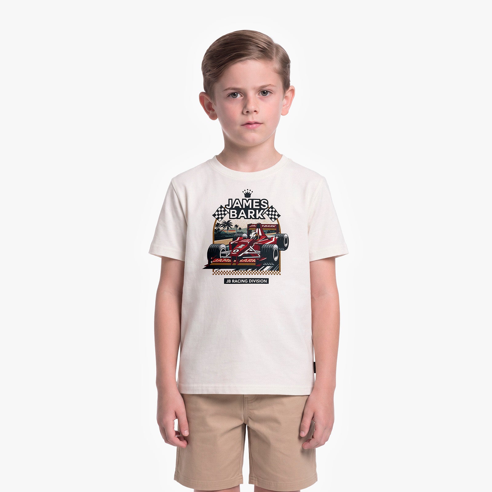 A young boy modeling a cream-colored t-shirt with a James Barker racing graphic, paired with khaki shorts