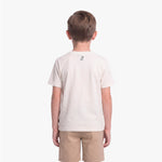 A child viewed from the back wearing a light cream/off-white short-sleeve t-shirt with a small black graphic on the upper back