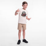 A young boy modeling a cream-colored graphic t-shirt, khaki shorts, and black sneakers against a plain white studio background.