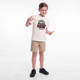 A young boy modeling a cream-colored graphic t-shirt, khaki shorts, and black sneakers against a plain white studio background.