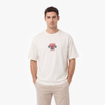 A man wearing a cream-colored crewneck t-shirt with a red and black 'James Spence Racing' chest graphic