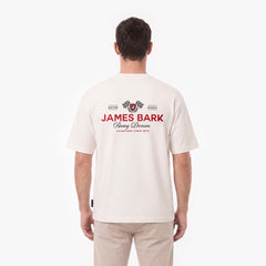 A man viewed from behind wearing a cream-colored short-sleeve t-shirt with a red and black James Bark Racing Division graphic on the back