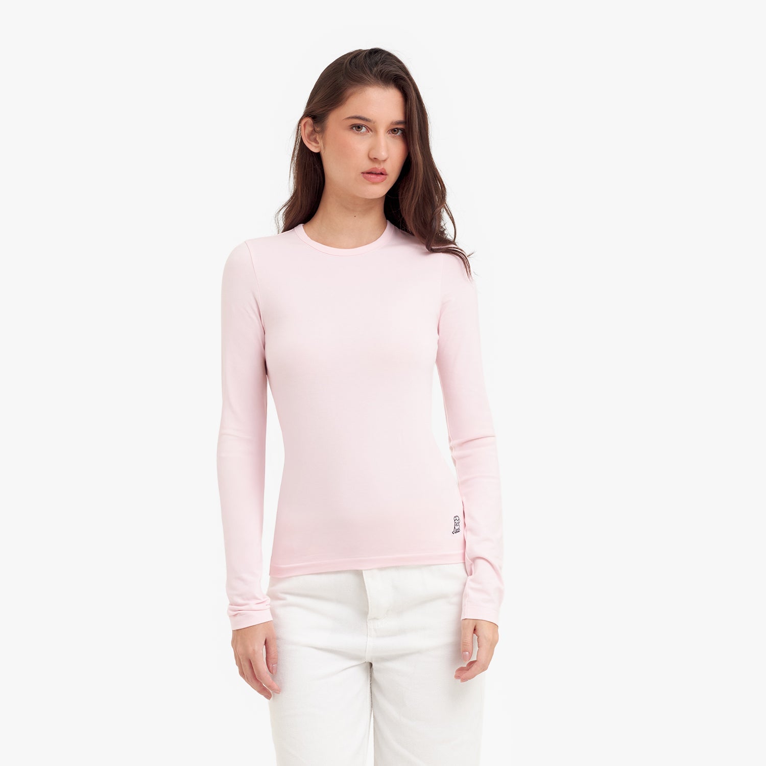 Woman wearing a light pink long-sleeve top and white pants on a white background