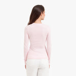 Back view of a woman wearing a light pink long-sleeve top on a white background