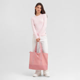 Woman holding a pink tote bag against a light gray background