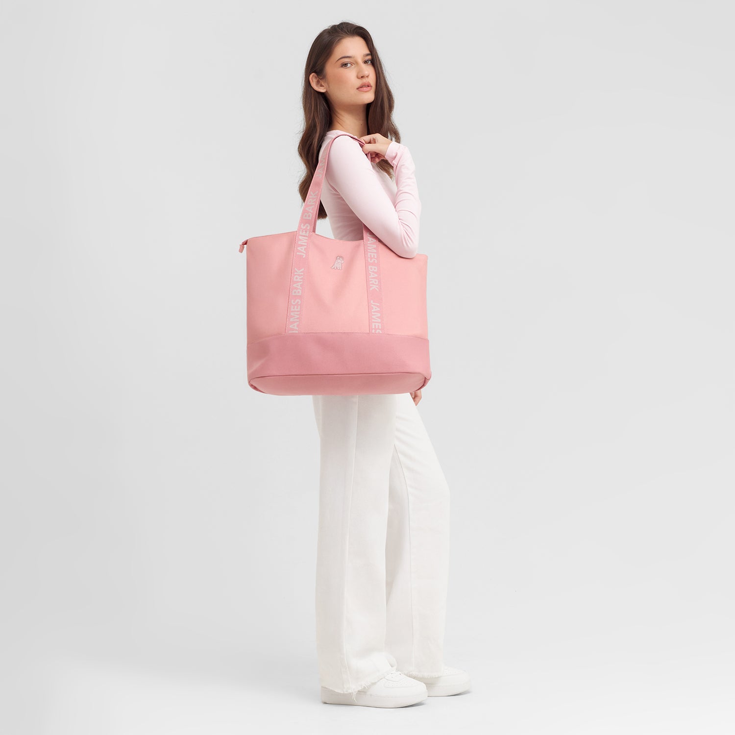 Woman holding a pink tote bag against a light gray background