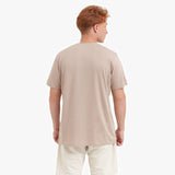 Back view of a man wearing a beige t-shirt on a white background