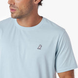 Close-up of a light blue t-shirt with a small logo on a white background
