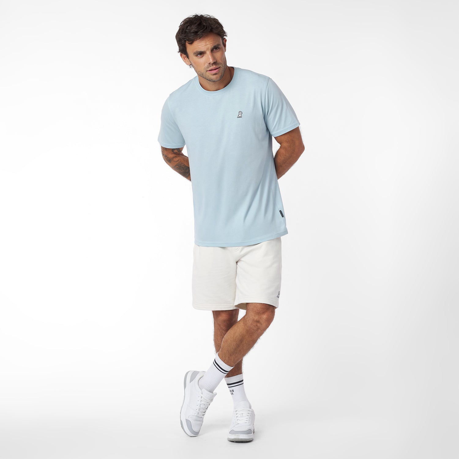 Man wearing a light blue t-shirt and white shorts on a white background