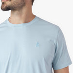 Close-up of a light blue t-shirt with a small logo on a white background